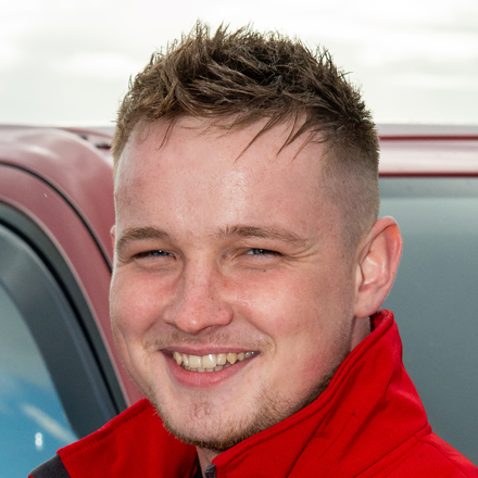 a person with a spiky hairstyle wearing a red jacket next to a car